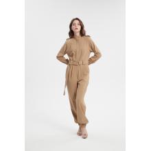 Mädchen gegen den Langarm -Jumpsuit mit Gürtel, den Jumpsuit mit Langschläfen.