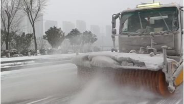 Snow brush and snow plow truck clearing road